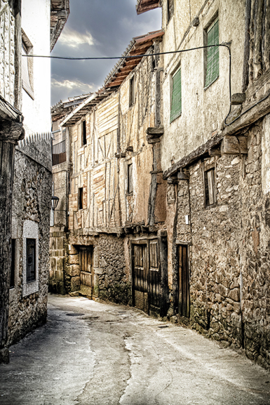Calle curva de Sequeros entre casas antiguas de piedra y revoco claro.