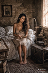 Chloe sentada sobre una cama en una habitación antigua, con vestido claro y luz cálida, serie Las Habitaciones de Chloe.