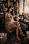 Chloe sentada junto a un escritorio o mesa de trabajo en una habitación antigua, con gesto tranquilo y ambiente doméstico.