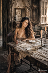 Chloe sentada frente a una mesa antigua con un plato y una botella, en una escena íntima de desayuno o comida ligera.