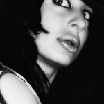 Retrato en blanco y negro de una mujer adulta con sombrero oscuro, mirada intensa y fuerte contraste de luces y sombras.