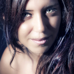 Retrato cercano de mujer adulta de cabello oscuro, iluminada lateralmente con una luz intensa sobre el rostro.