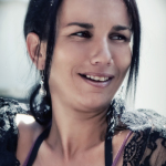 Retrato de mujer adulta con prenda de encaje negro, sonriendo mientras mira hacia un lado.