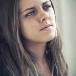 Retrato de mujer adulta junto a una ventana, con expresión pensativa y luz suave sobre el rostro.