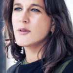 Retrato de mujer adulta con cabello oscuro, captada con la boca entreabierta y mirada hacia la luz exterior.