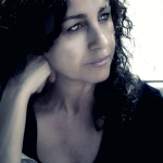 Retrato de mujer adulta con cabello rizado, apoyando la cabeza en la mano y mirando hacia un lado.
