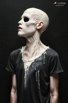 Figura de perfil con rostro pálido y sin ojos visibles, piel surcada por líneas profundas y materia clara derramada sobre una camiseta negra.