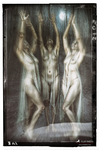 Tres brujas desnudas con velos claros elevan los brazos en un bosque oscuro, como parte de una invocación ritual.