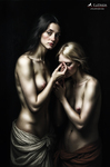 Dos mujeres desnudas en una escena íntima, una de ellas inclinada hacia la mano de la otra en un gesto delicado y contemplativo.