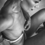 Desnudo femenino en blanco y negro, con el cuerpo inclinado y una mano junto a la ropa interior.