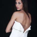 Mujer adulta de espaldas, envuelta en una tela blanca, girándose hacia la cámara.