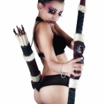 Mujer adulta con vestuario de fantasía y un arco, en una pose de estudio sobre fondo claro.