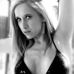 Retrato de mujer adulta rubia con un brazo elevado y mirada intensa, en una imagen en blanco y negro.