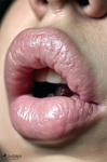 Primer plano de labios rosados entreabiertos, con brillo intenso y luz clara sobre la piel.