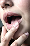 Primer plano de una boca entreabierta con dos dedos apoyados en los labios, en una imagen de gesto sensual.