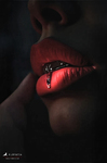 Primer plano de labios rojos con la lengua ligeramente fuera y un dedo junto a la boca, en una escena oscura.