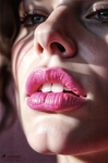 Primer plano de labios rosados con sombras marcadas sobre el rostro y mirada parcialmente visible al fondo.