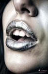 Primer plano de una boca con labios maquillados en tonos plateados y oscuros, sobre piel pálida.