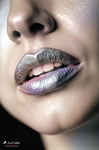 Primer plano de labios con maquillaje metálico y la lengua ligeramente visible, en una imagen de brillo frío y sensual.