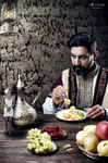Hombre barbado sentado a la mesa con comida y fruta delante, en una escena de laboratorio doméstico y aire antiguo.