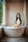 Mujer adulta sentada dentro de una bañera blanca en un baño de paredes envejecidas y luz natural.