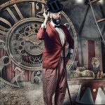 Hombre con chaqueta roja y sombrero en un decorado de engranajes y reloj antiguo, con gesto teatral.