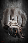 Pequeña figura de un hombre adulto en silla de ruedas, sostenida sobre la palma de una mano gigante.