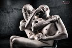 Composición de dos cuerpos masculinos desnudos entrelazados en una escena oscura y escultórica.