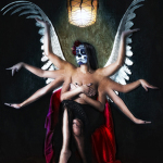 Mujer adulta caracterizada como Catrina, con alas y varias manos extendidas a su alrededor en una composición fantástica.