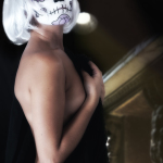 Detalle del torso y la espalda de mujer adulta con maquillaje de calavera, en una escena de luz cálida y desenfoque suave.