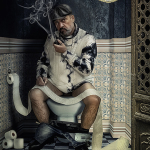 Hombre adulto sentado en un inodoro, con camiseta blanca manchada y gorra, en un baño antiguo de atmósfera decadente.