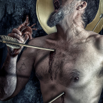 Hombre semidesnudo con varias agujas o varillas atravesando visualmente el cuerpo, con la cabeza inclinada hacia atrás.