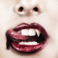 Primer plano de una boca femenina con labios rojos brillantes y líquido oscuro descendiendo desde la boca.