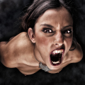 Mujer adulta inclinada hacia la cámara con la boca abierta, en una pose agresiva de estética vampírica.