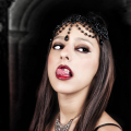 Retrato de mujer adulta con labios rojos y mirada intensa, en una imagen de estética vampírica.