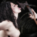 Mujer adulta inclinando el cuello hacia un cuchillo o estaca, en una imagen de tensión vampírica.