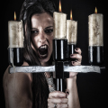 Mujer adulta con rostro oscuro y mirada intensa, rodeada por velas o candelabros.