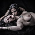 Dos mujeres adultas en el suelo, una inclinada sobre la otra en una escena de mordida o ataque vampírico.