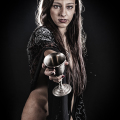 Mujer adulta ofreciendo una copa hacia la cámara, en una escena de vampiros y seducción oscura.