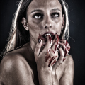 Mujer adulta con sangre en las manos y la boca, en una imagen de vampirismo explícito y oscuro.