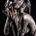 Mujer adulta con sangre en las manos, el cuello y el rostro, en una escena oscura de vampirismo.