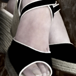 Primer plano unos pies femeninos con zapatos negros y blancos de corte alto.