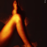 Piernas femeninas desenfocadas en tonos anaranjados, con un fuerte efecto de luz cálida.