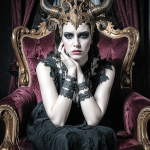 Mujer adulta sentada en un gran sillón o trono ornamentado, con expresión severa y vestuario oscuro.