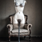 Torso de maniquí femenino colocado sobre una butaca, en una composición surreal y deshumanizada.