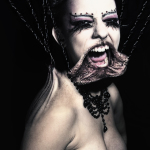 Retrato de una mujer monstruosa con la boca deformada y abierta en un grito, sobre fondo oscuro.