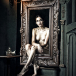 Mujer adulta desnuda sentada dentro de un marco de madera, en un interior oscuro con velas u objetos al fondo.