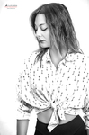 Retrato en blanco y negro de mujer adulta con camisa clara estampada, mirando hacia abajo con expresión serena.