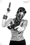 Retrato en blanco y negro de mujer adulta con gafas redondas y accesorios llamativos, posando con dos pistolas en una actitud teatral.