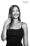 Retrato en blanco y negro de mujer adulta sonriendo, sosteniendo una cuchara u objeto pequeño junto al rostro.